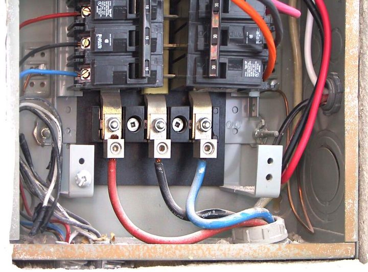 The inside of a breaker panel with the cover removed, showing the bus bars, the lugs and the heavy service conductors feeding them.