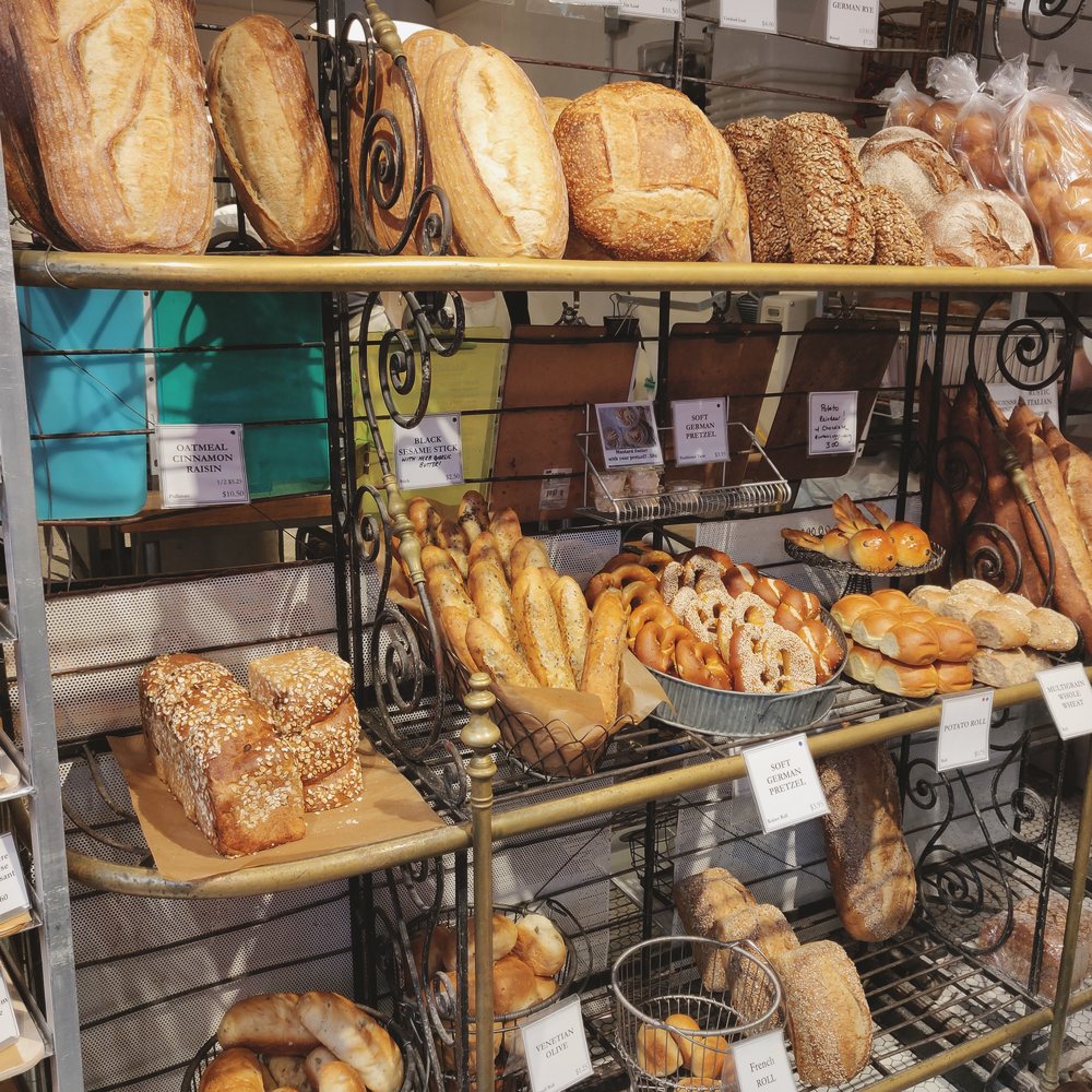 Bakery shelves stacked with loaves and pastries.