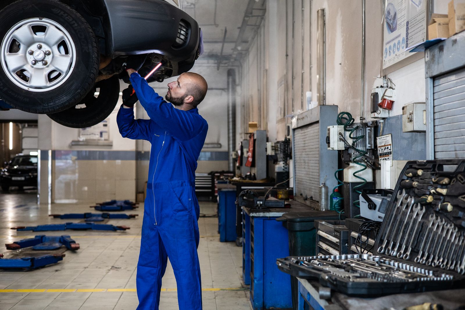 A technician working on a wheel of a vehicle raised on a lift.