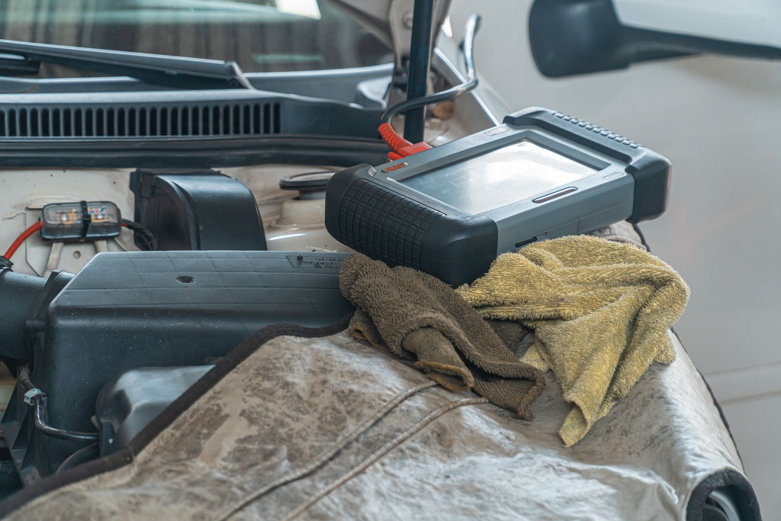 A diagnostic scan tool resting on an engine during testing.