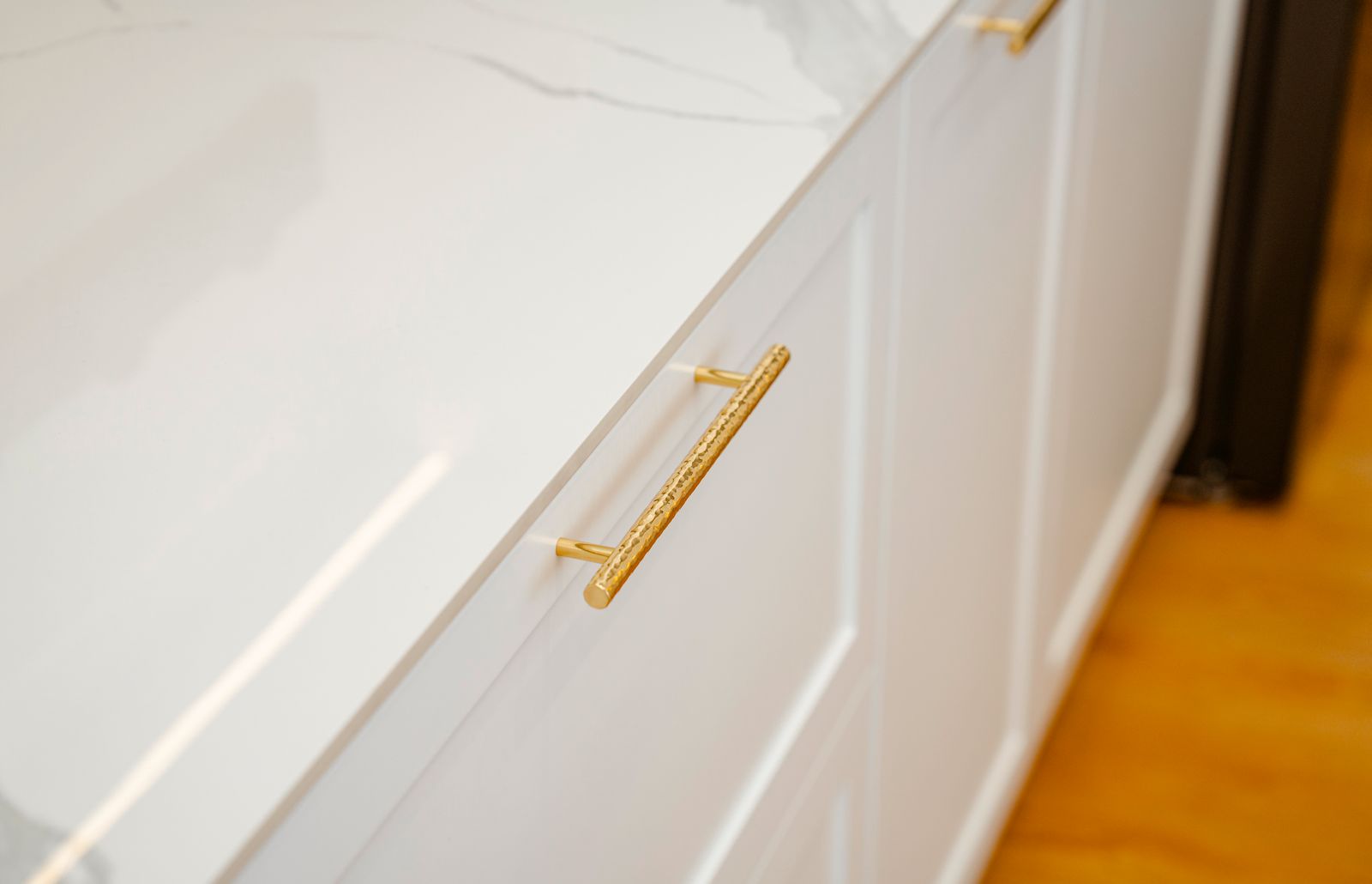 Close view of a cabinet door with an unlacquered brass pull.