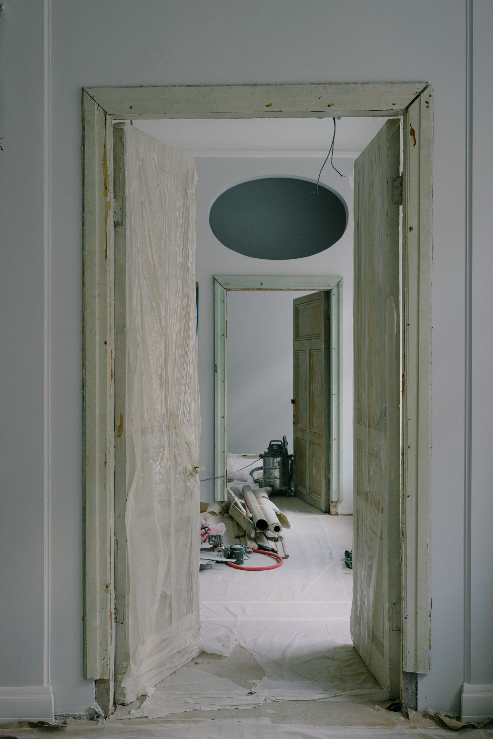 A doorway and adjoining room mid-renovation with trim removed and surfaces bare.