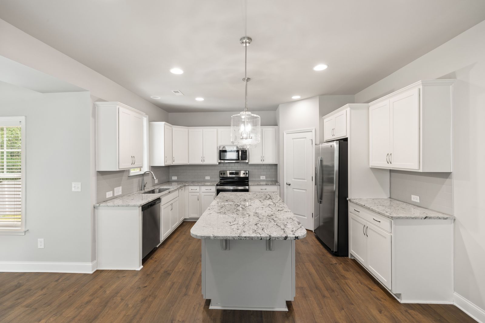 The finished kitchen with island and stone counters seen from the dining side.