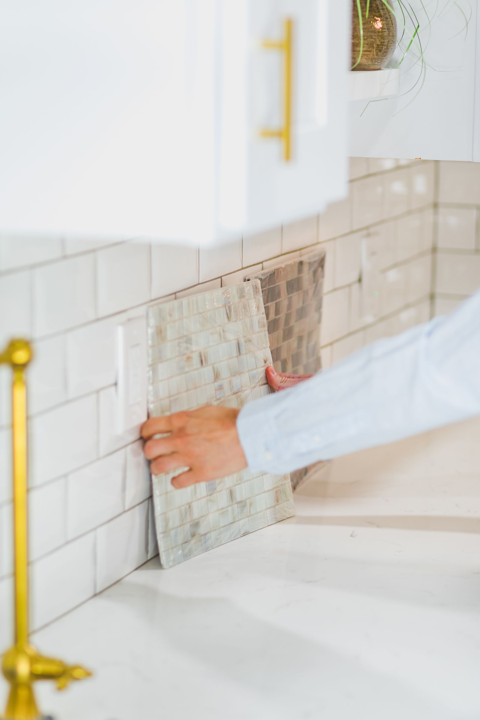 Hands setting tile into fresh adhesive.
