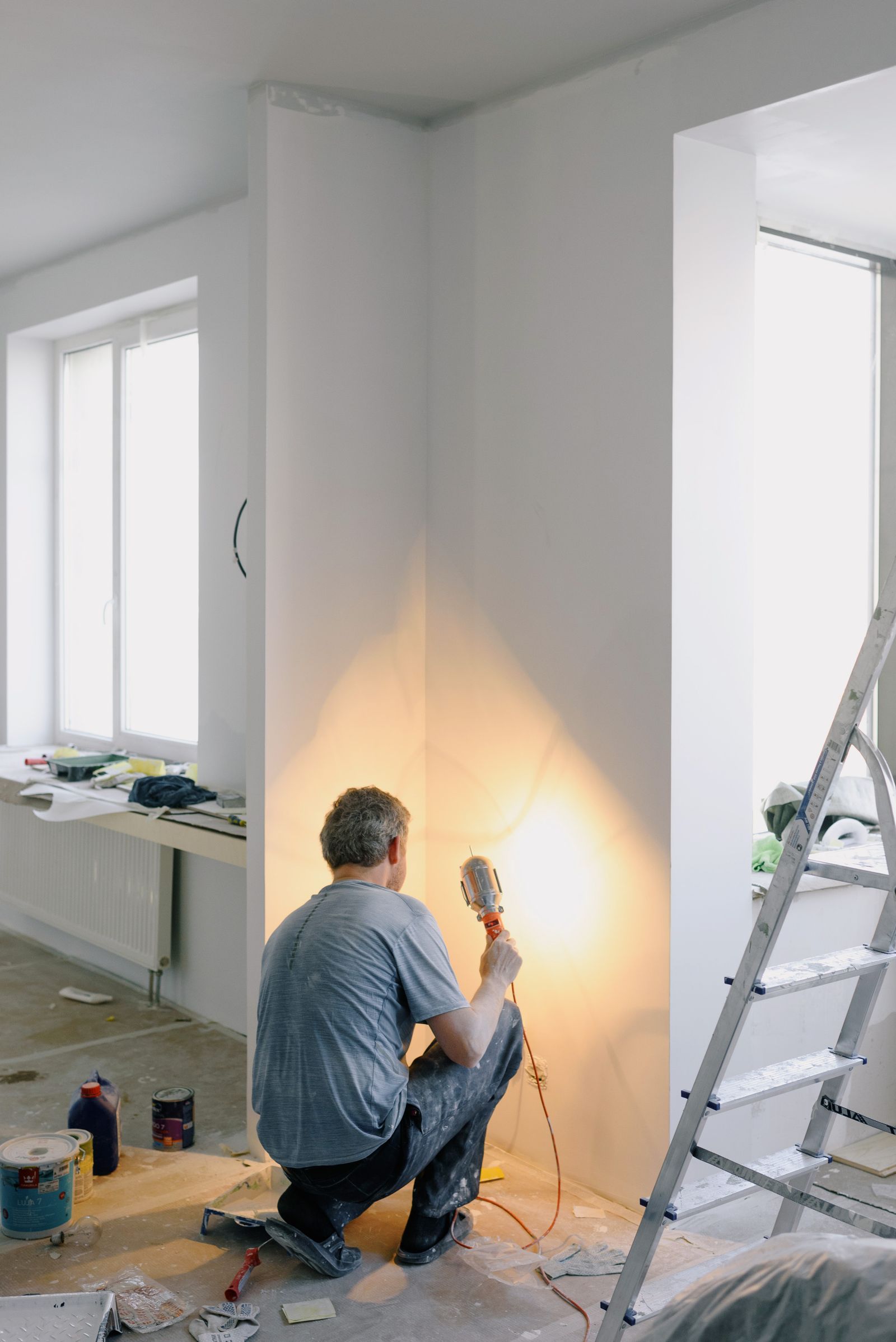 A tradesman finishing a wall surface under work lighting.