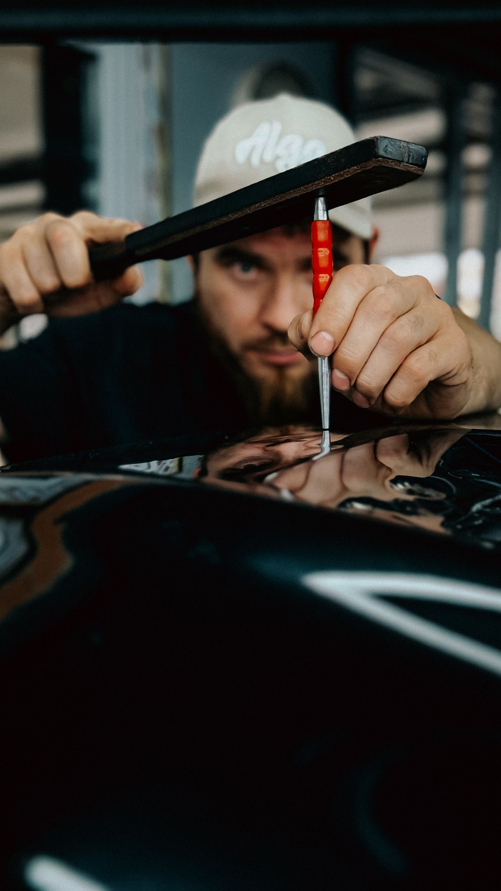 A technician working on a vehicle panel with a small tool