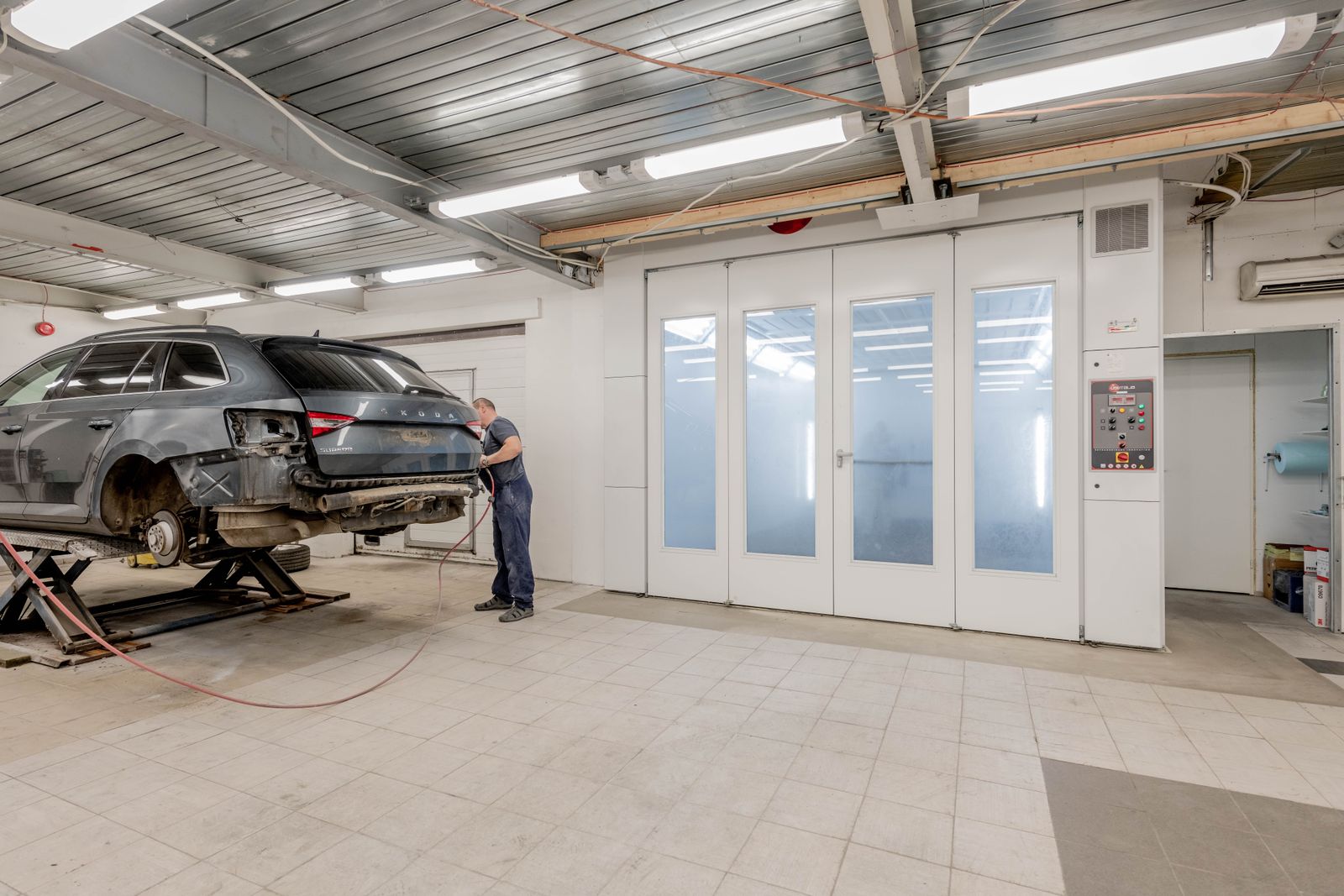 A disassembled car beside an enclosed automotive paint booth