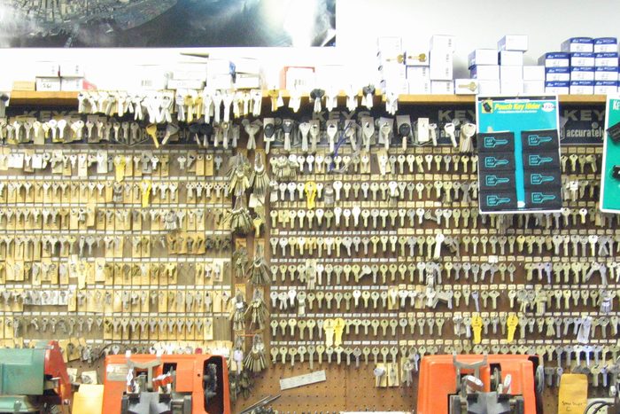 A locksmith counter: a full wall of key blanks hanging on hooks behind two bench-mounted key cutting machines.