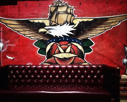 A traditional eagle mural above a red leather bench