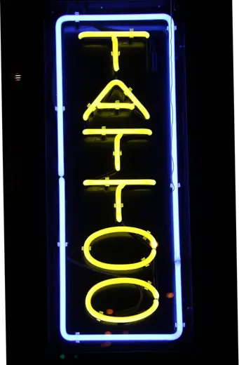 A vertical neon sign that reads TATTOO