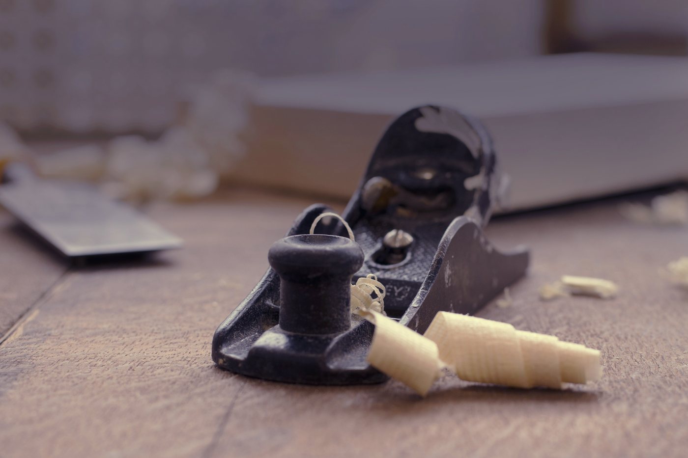 A block plane lying on its side on a bench beside the shaving it has just taken off a board