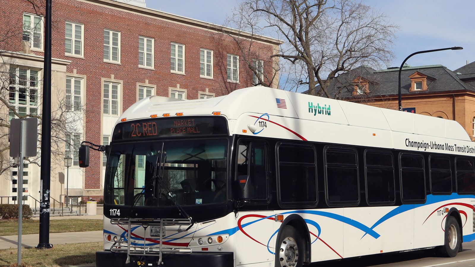 A low-floor city bus pulled up at a curb on a wide street, doors on the near side