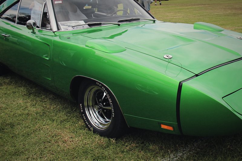 A green 1969 Dodge Charger Daytona with its high rear wing, photographed from the side.