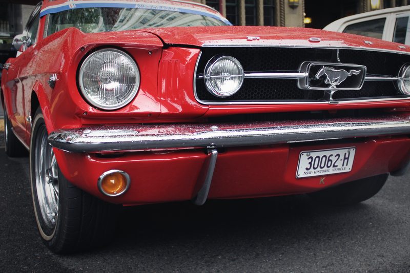 A red 1965 Ford Mustang photographed head-on.