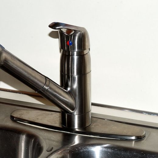 A newly fitted pull-down kitchen faucet on a stainless steel sink.