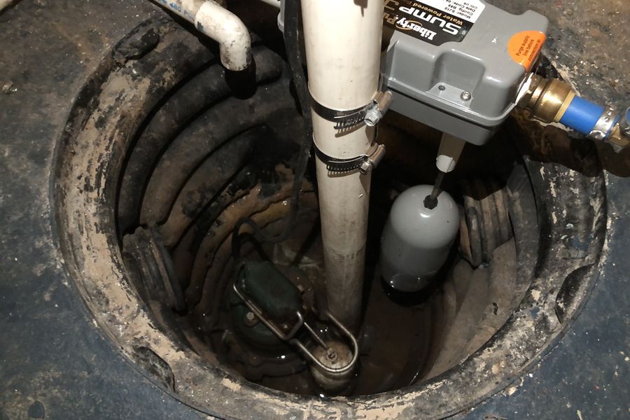 A newly installed sump pump sitting in an open basement pit with its discharge pipe and check valve.